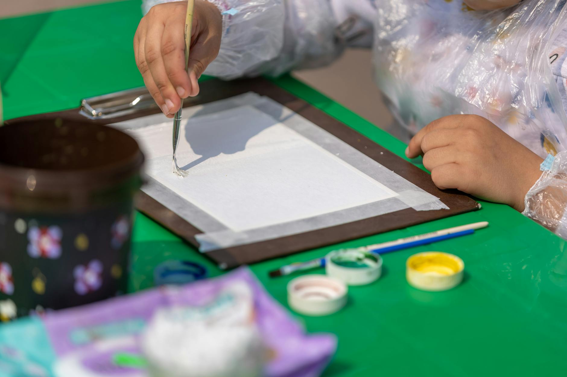 Dziecko malujące akwarelami na dworze w słoneczny dzień