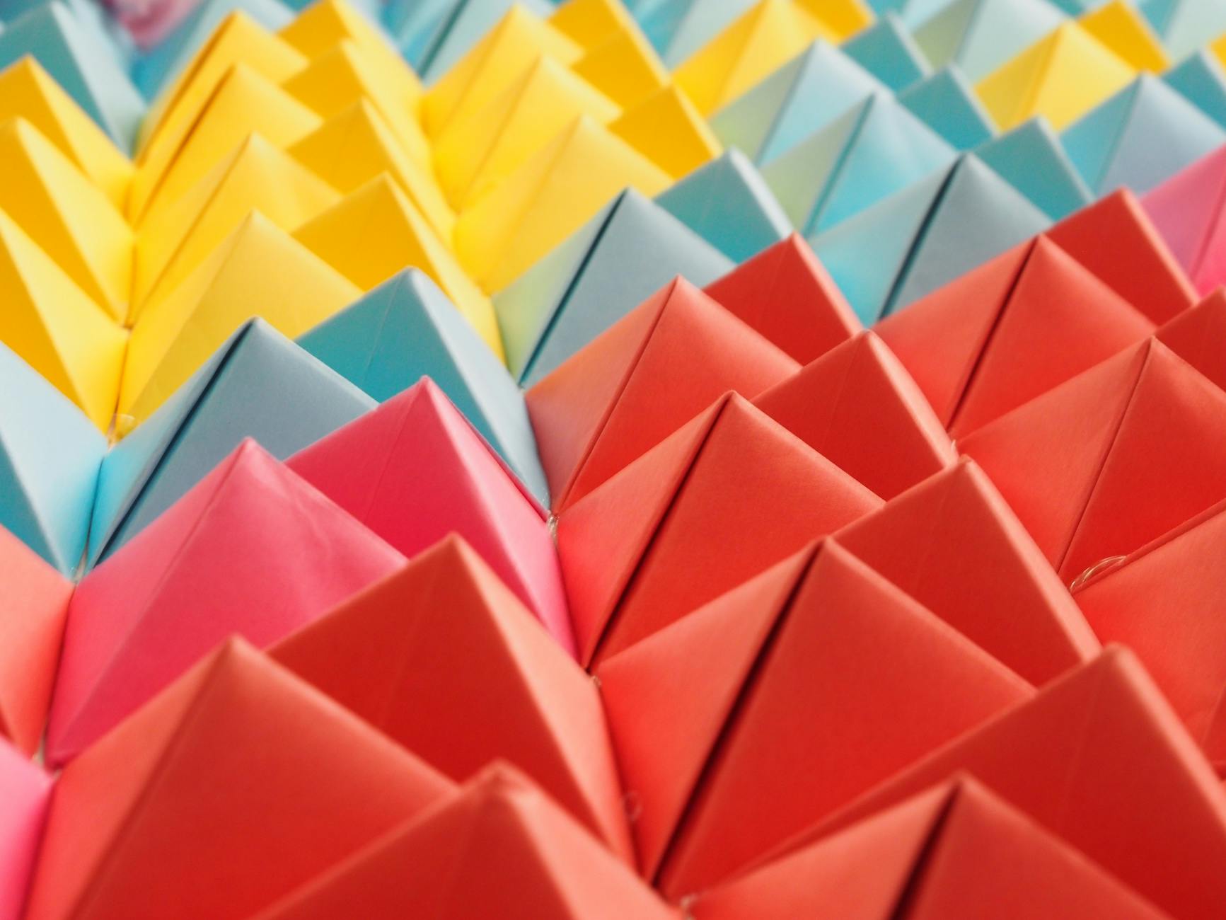 Kolorowe papierowe piramidki origami ułożone w geometryczny wzór