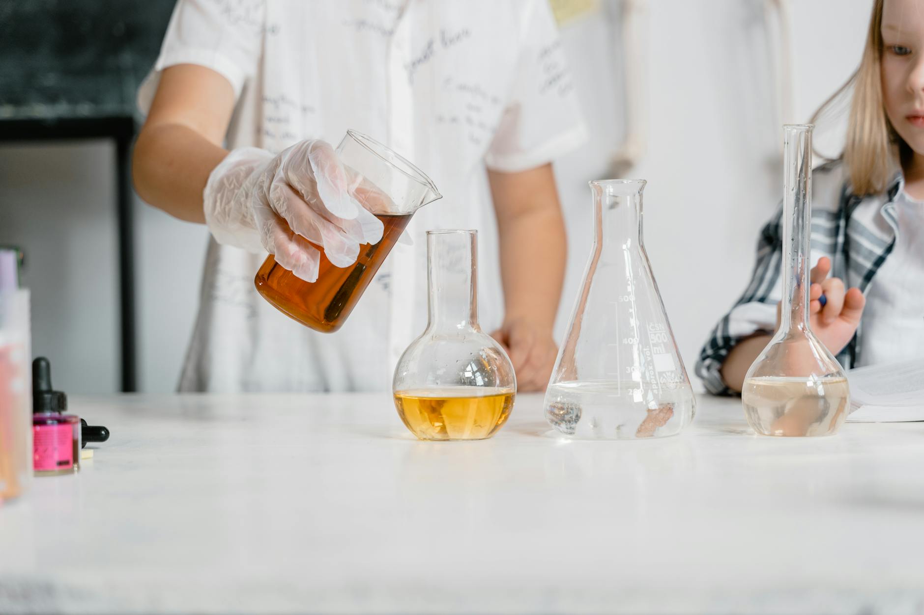 Dzieci w szkolnym laboratorium badają roztwory w zlewkach