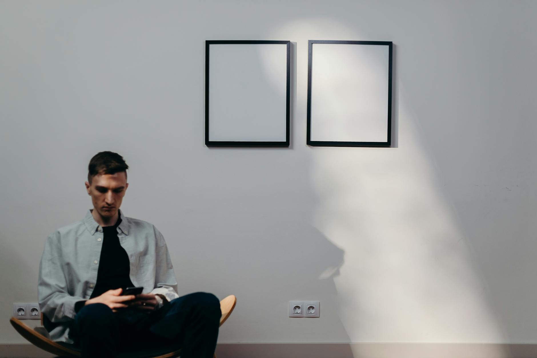 Mężczyzna w nowoczesnym pokoju z dwiema pustymi ramami na ścianie