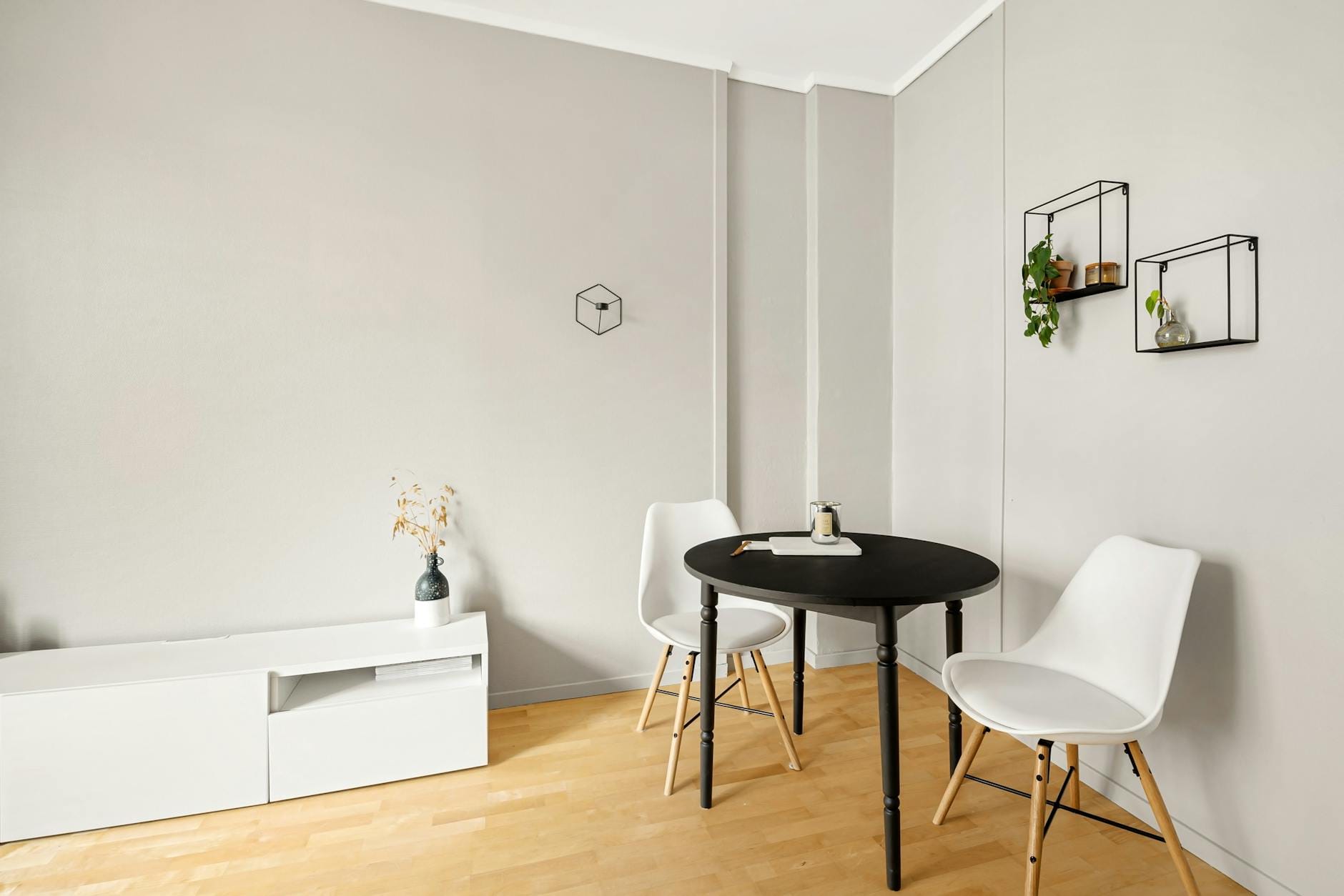 Minimalistyczny salon z czarnym stołem i białymi krzesłami na jasnej podłodze