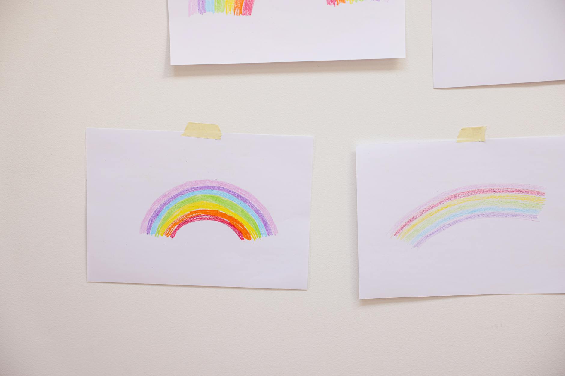 Ręcznie narysowana tęcza na kartce przyklejonej do białej ściany