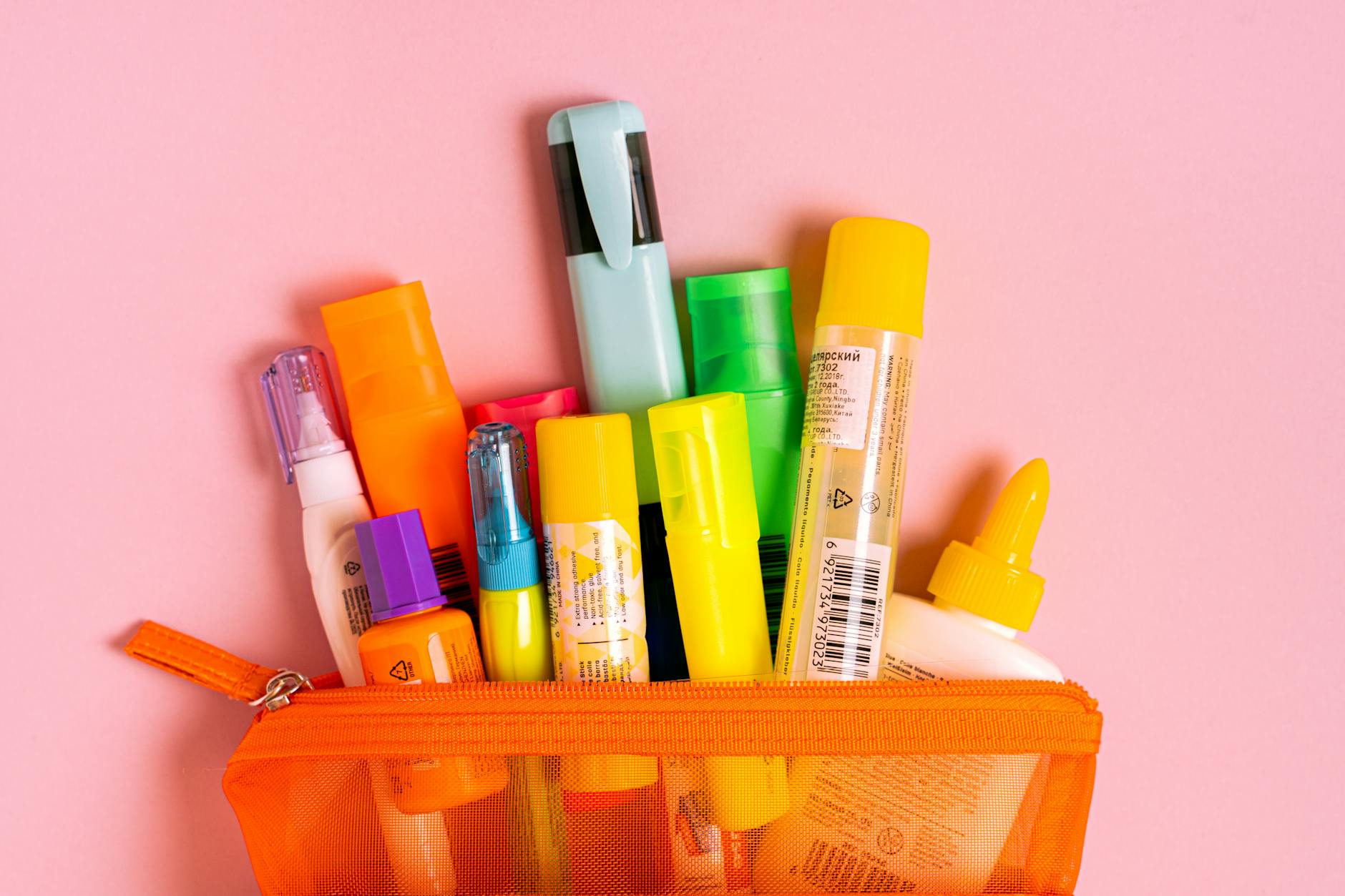 Różowe biurko z siatkową kosmetyczką pełną kolorowych przyborów szkolnych