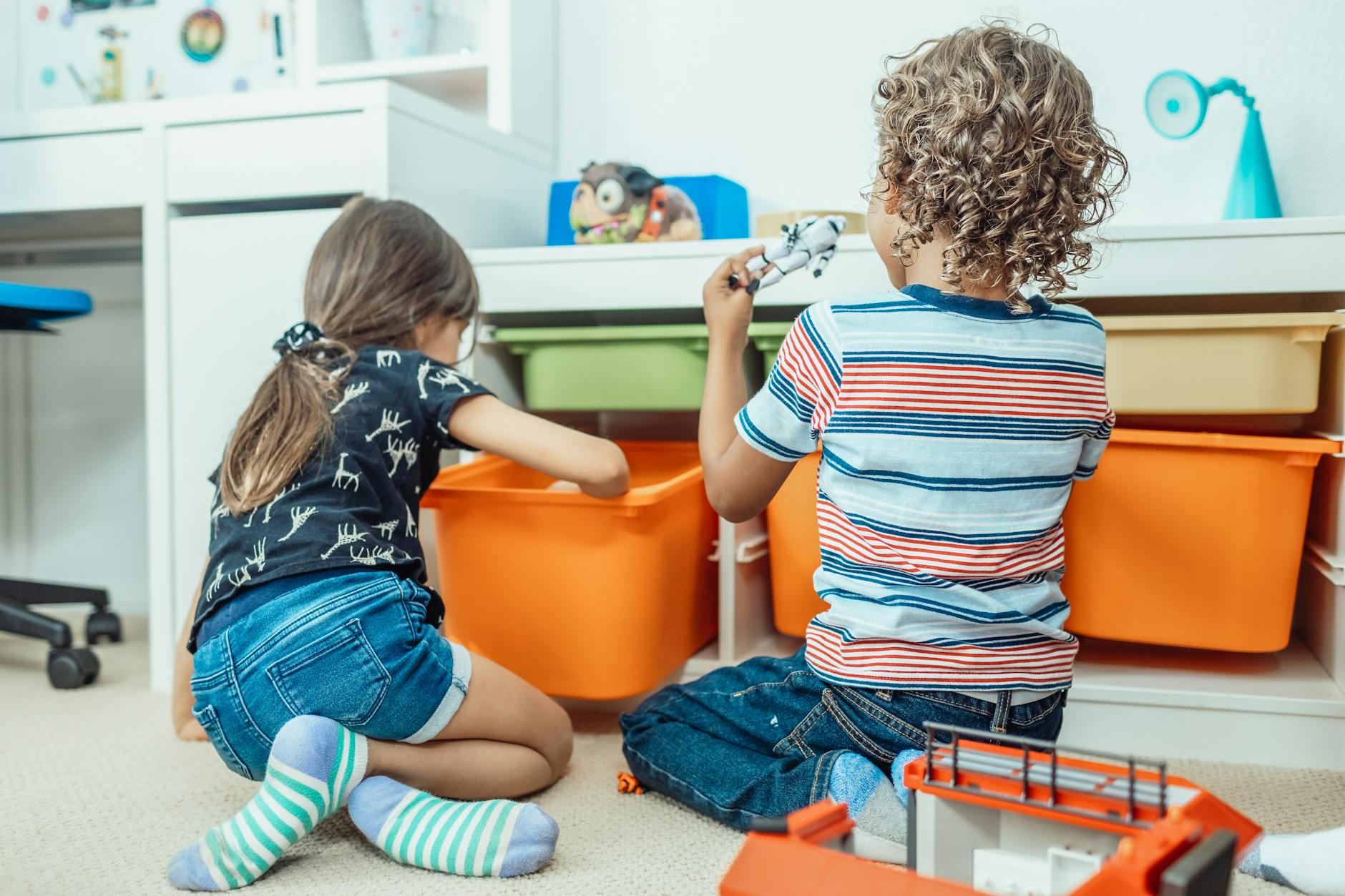 Dwoje dzieci bawi się zabawkami i kolorowymi pojemnikami w pokoju