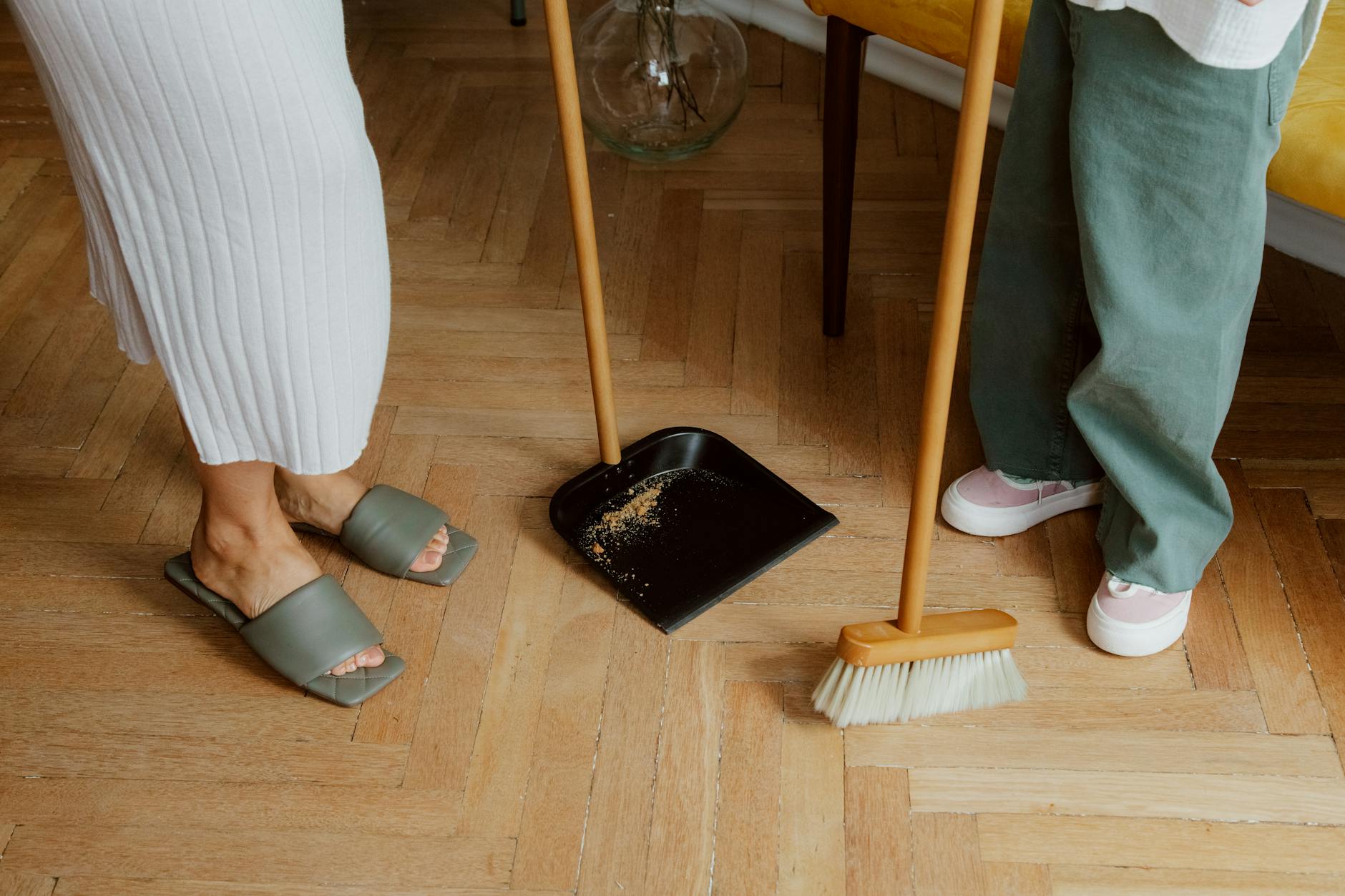 Mama i dziecko zamiatają razem podłogę w pokoju