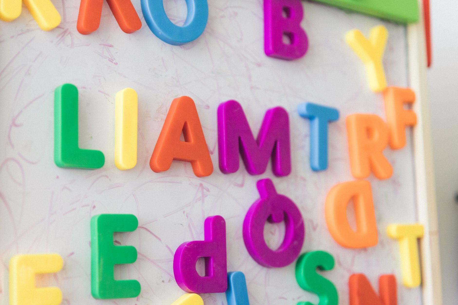 Kolorowe magnetyczne literki ułożone na białej tablicy